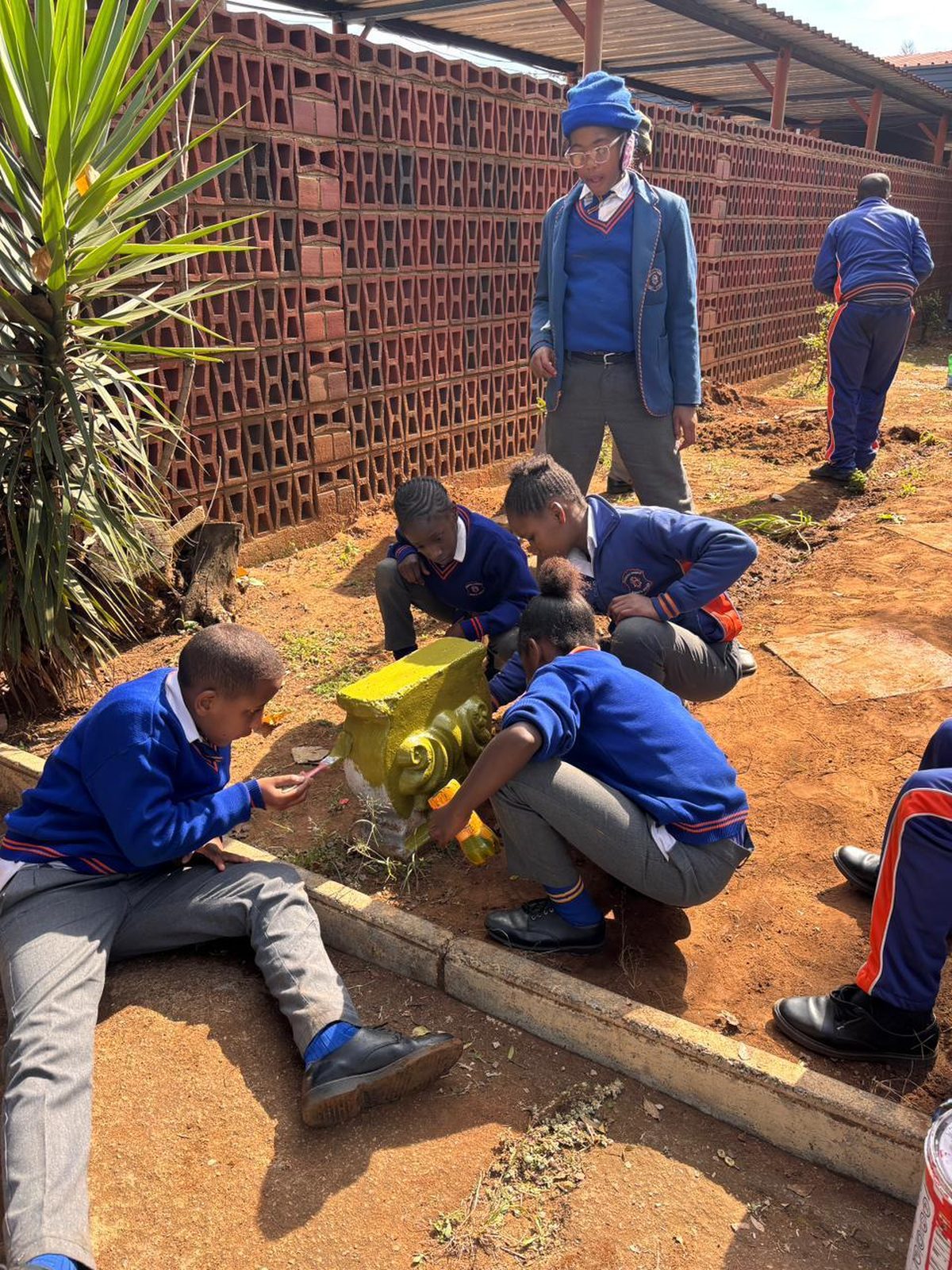 Learners painting a garden ornament gold in their new green space