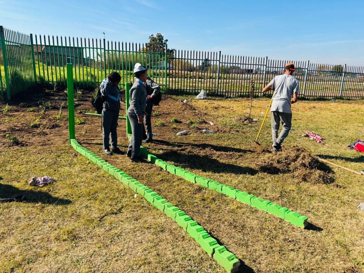 Learners setting out the green kerb edging that marks the boundary of their new garden